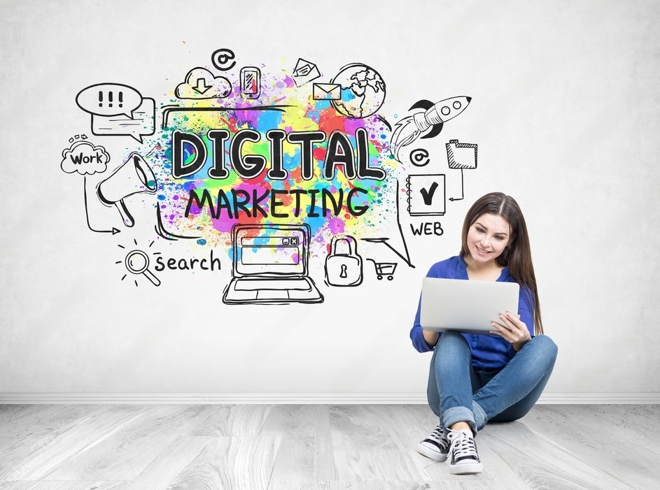 A person working on a laptop in front of a wall with vibrant digital marketing graffiti
